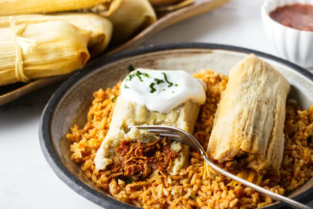Two tamales on a plate with Mexican rice. 