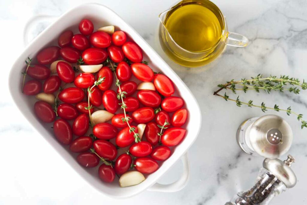 tomatoes in a dish, pitcher of olive oil, thyme sprigs, salt and pepper.