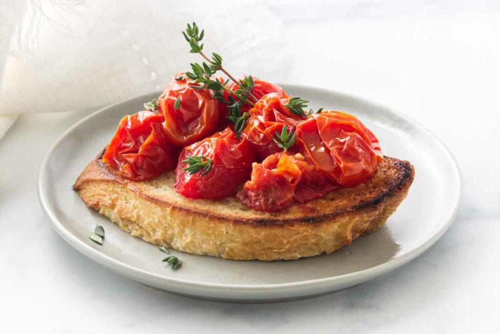 A small appetizer plate with conti tomato bruschetta garnished with fresh thyme sprigs.