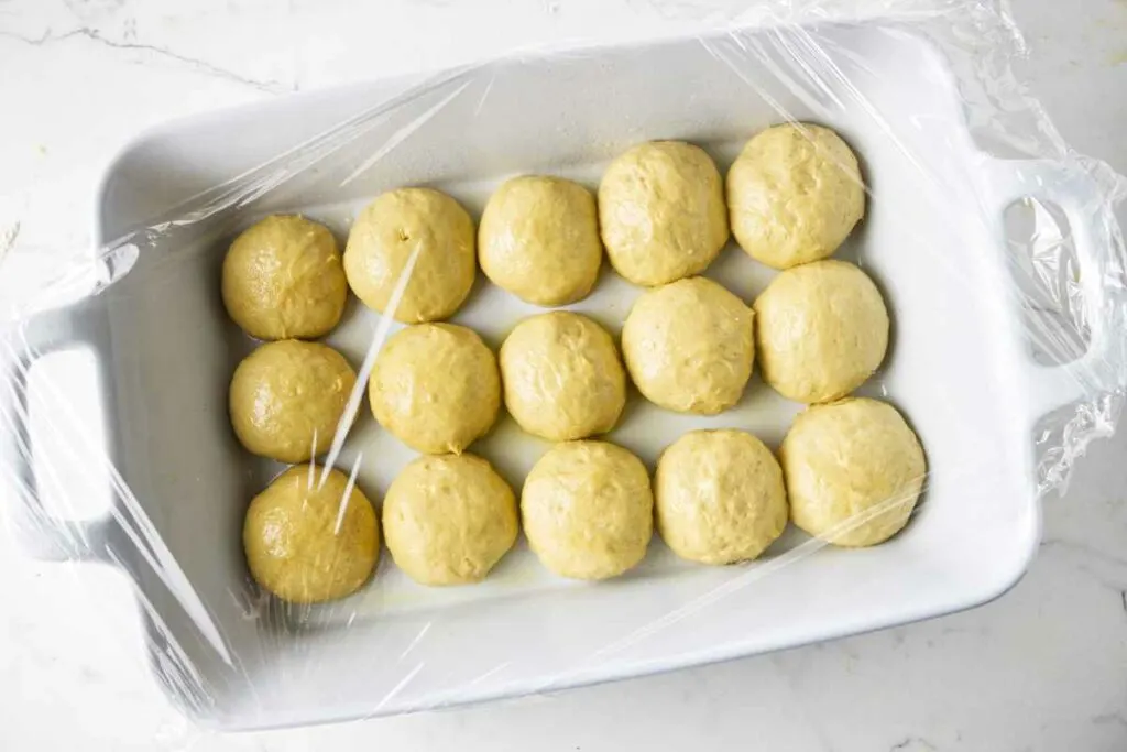 Balls of bread dough in a baking dish.