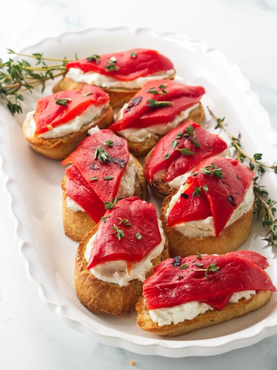 Eight bruschetta with red pepper and goat cheese.