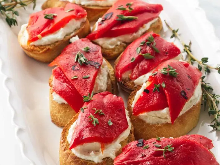 Eight bruschetta with red pepper and goat cheese.