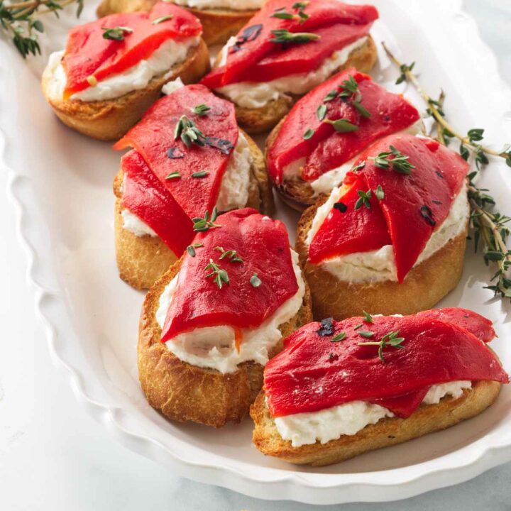 Several roasted red pepper bruschetta appetizers on a serving platter.