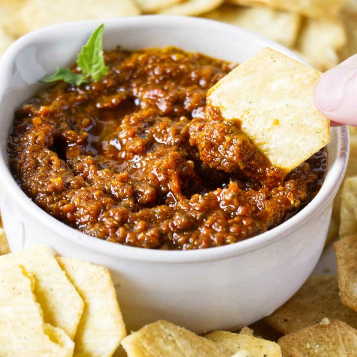 Dipping a chip into a dish of sundried tomato pesto.