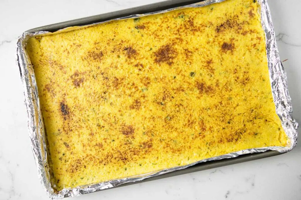 Polenta browned in the oven after being spread in a sheet pan.