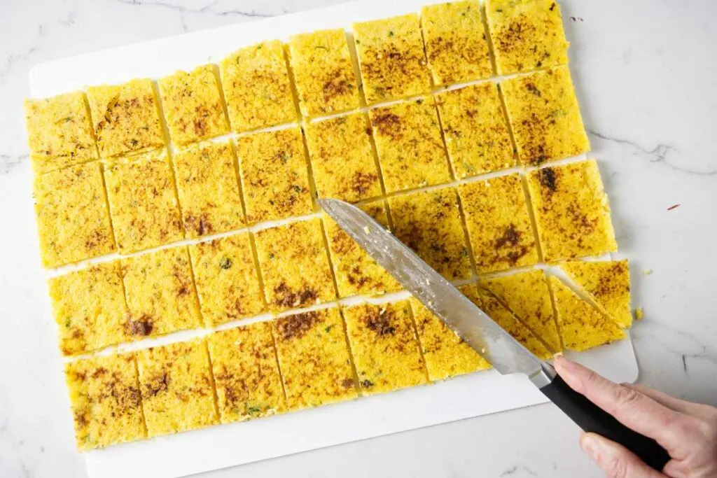 Slicing firm polenta into small appetizer sized canapes.