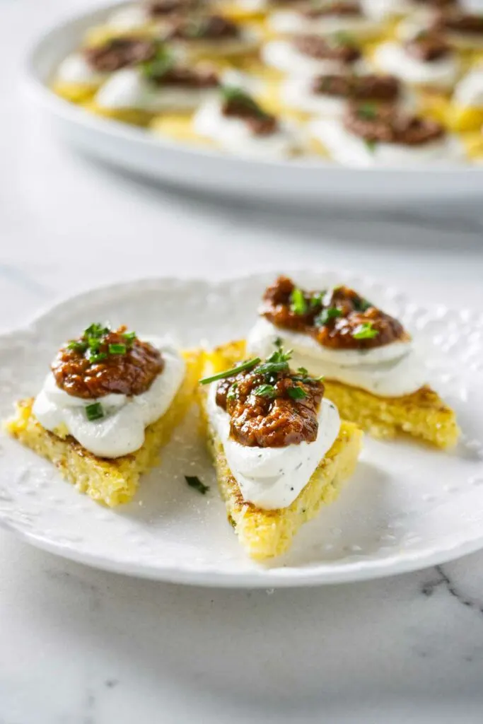 Several polenta canapes on a plate.