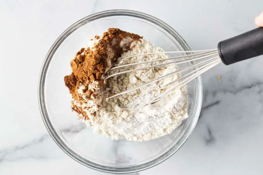 Blending the flour, spices, salt, baking powder and baking soda together with a wire whisk.