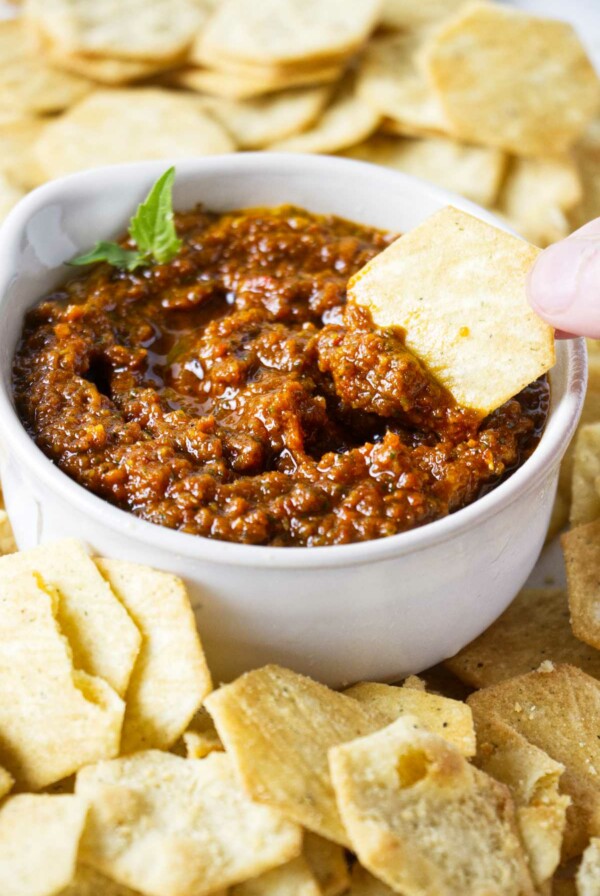 Dipping a chip into a bowl of sun dried tomato pesto.