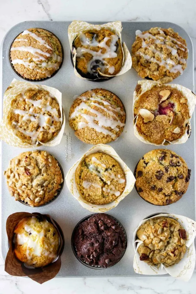 A muffin pan filled with twelve different types of muffins.