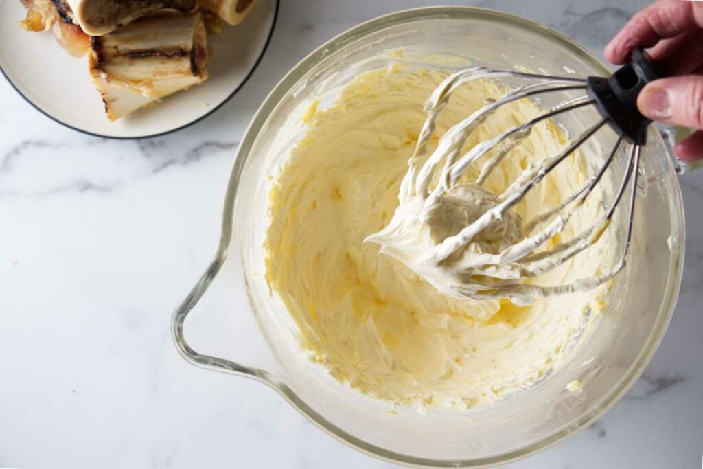 A bowl of whipped butter and a whisk.