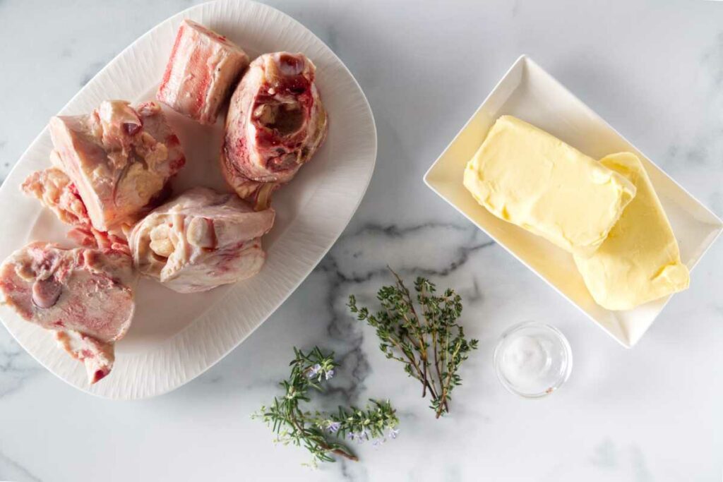 Beef Bone marrow bones, butter, sprigs of fresh rosemary, thyme and a small dish of salt.