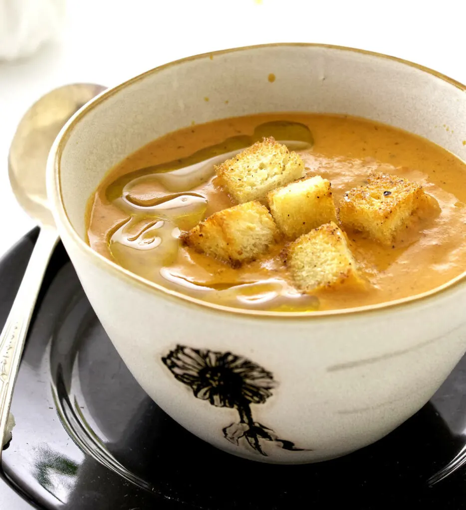 A bowl of soup topped with croutons.