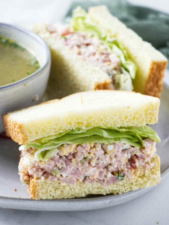 A ham salad sandwich next to a bowl of soup.