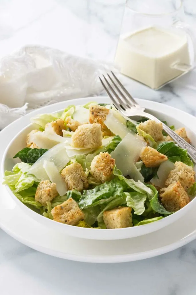 A salad bowl filled with Caesar salad and topped with homemade croutons.
