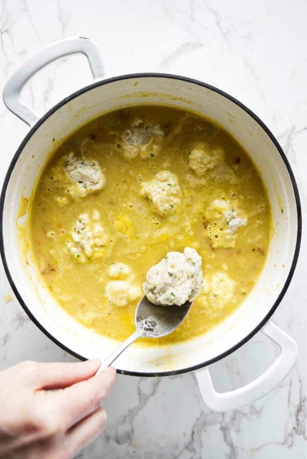 Dropping dumpling batter into a pot of simmering soup.