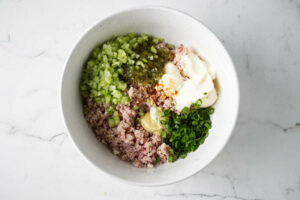 Combining the ingredients for a minced ham salad.
