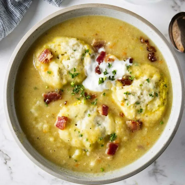 A bowl of potato soup with dumplings and bacon.