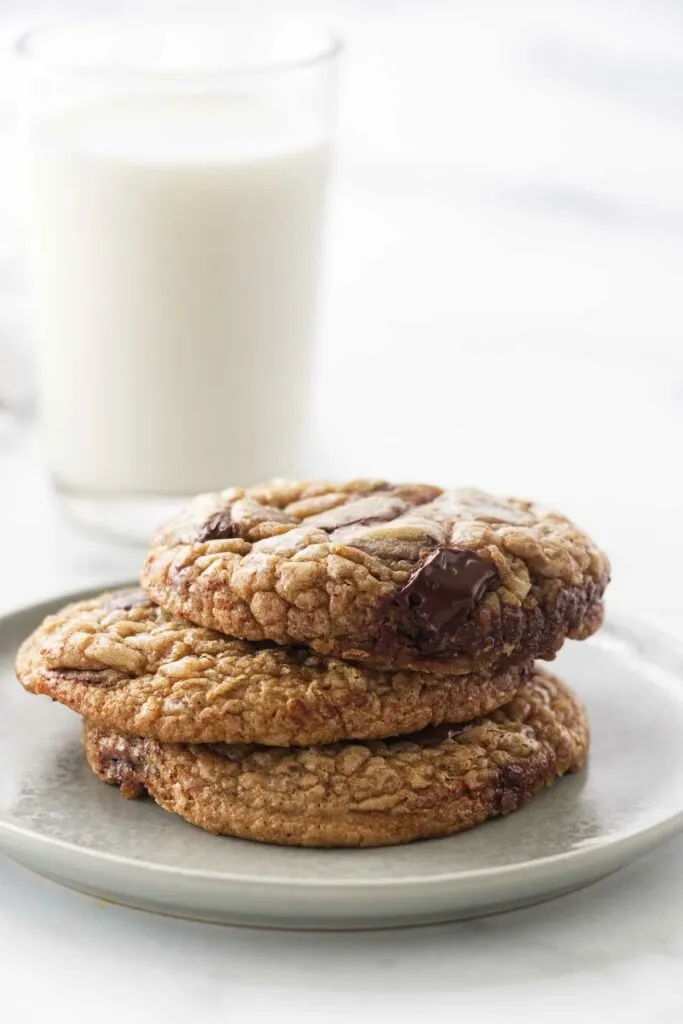 A stack of chocolate chip cookies in front of a glass of milk.