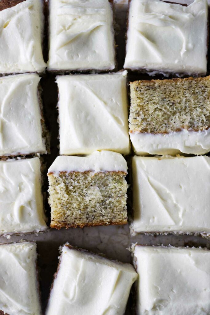 Several slices of snack cake topped with cream cheese frosting on a counter.