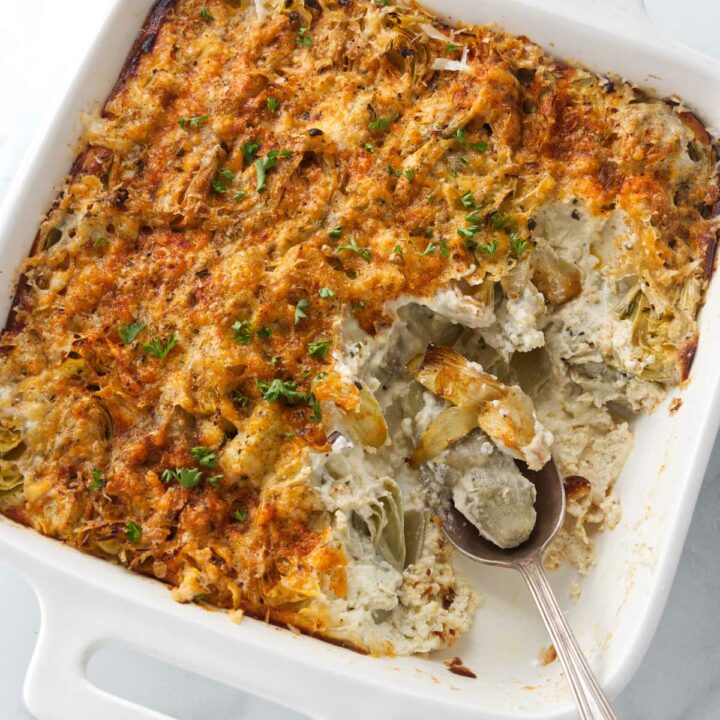 A spoon scooping out a serving of artichoke and ricotta gratin.