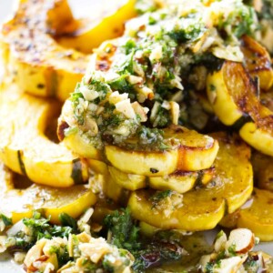 A serving platter with delicata squash topped with brown butter and a gremolata.