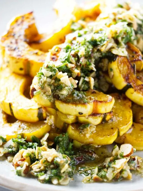 A serving platter with delicata squash topped with brown butter and a gremolata.
