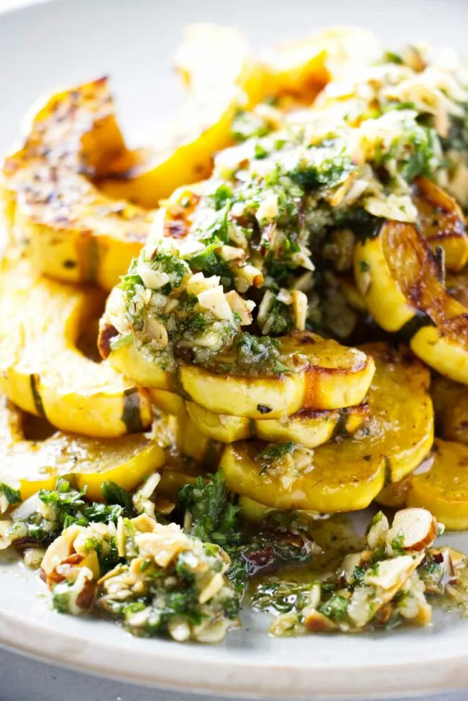 A serving platter with delicata squash topped with brown butter and a gremolata.