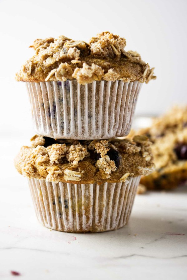 Two whole grain banana blueberry muffins stacked on top of each other.