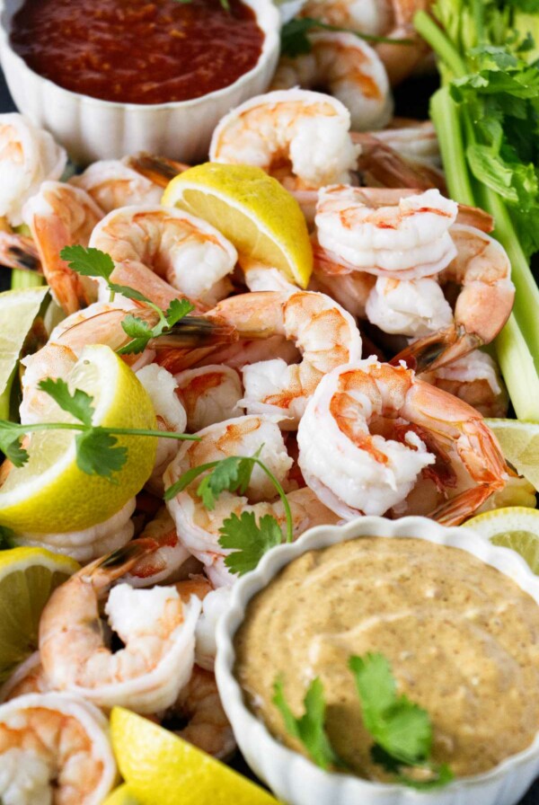 Boiled shrimp on a platter with lemon slices and cocktail sauce.