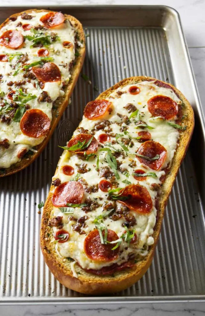 Two loaves of garlic bread pizza on a baking sheet.