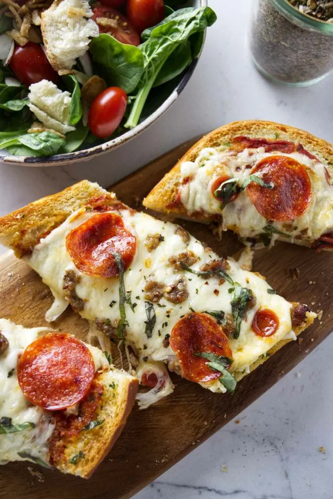 Three slices of garlic pizza bread next to a bowl of salad.