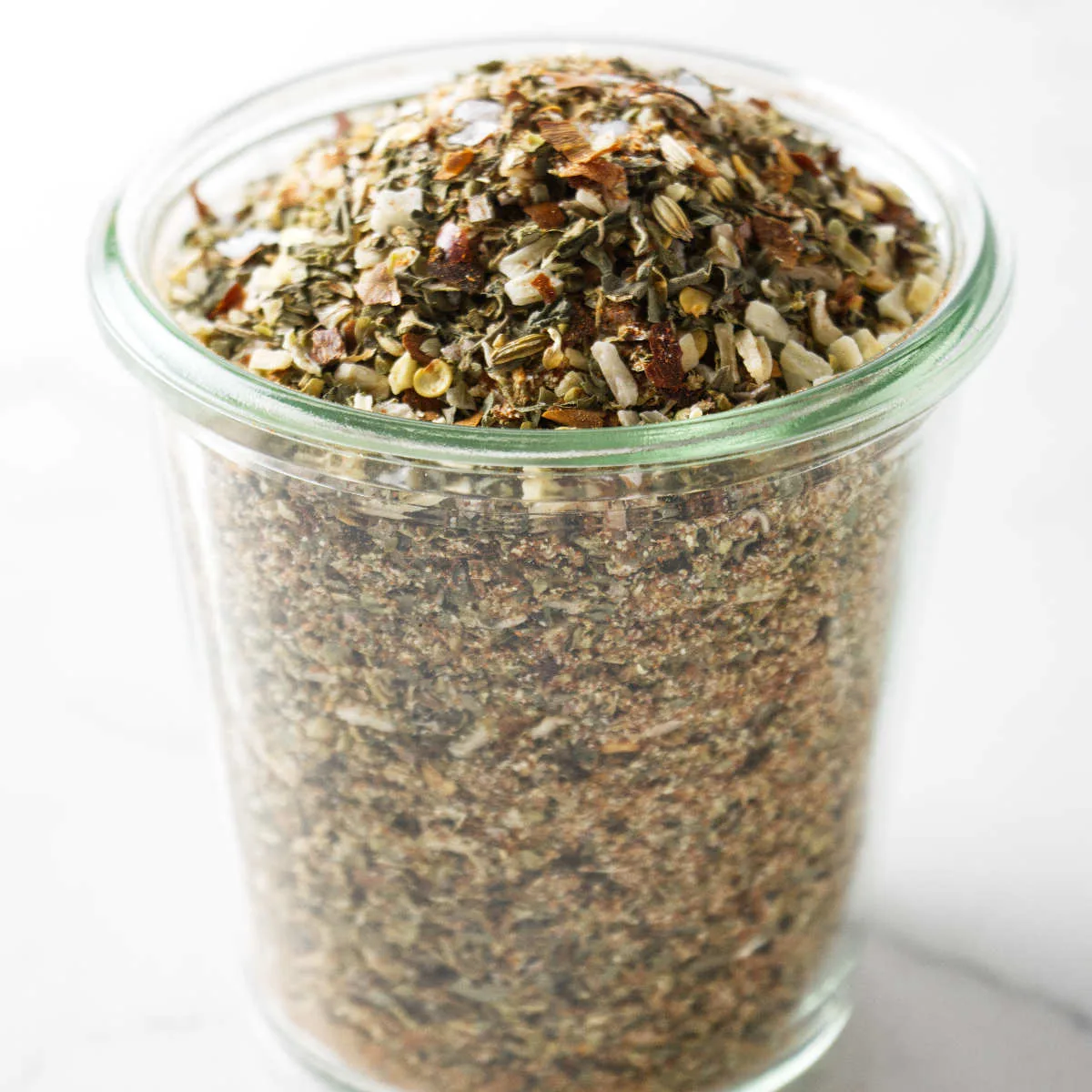 A jar filled with homemade pizza seasoning.
