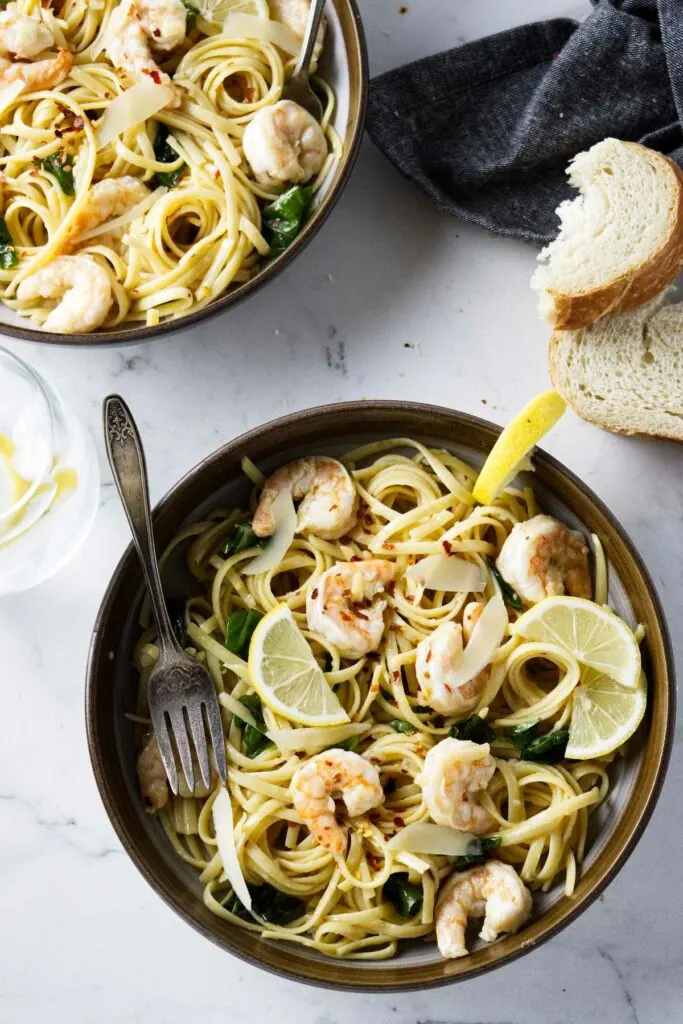 Two pasta bowls filled with garlic lemon shrimp pasta.