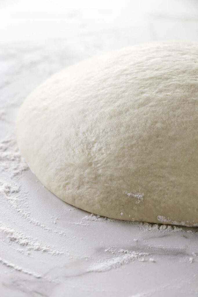 Pizza dough on a floured counter.