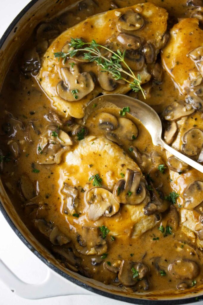 A skillet filled with chicken marsala made with fresh and dried mushrooms.