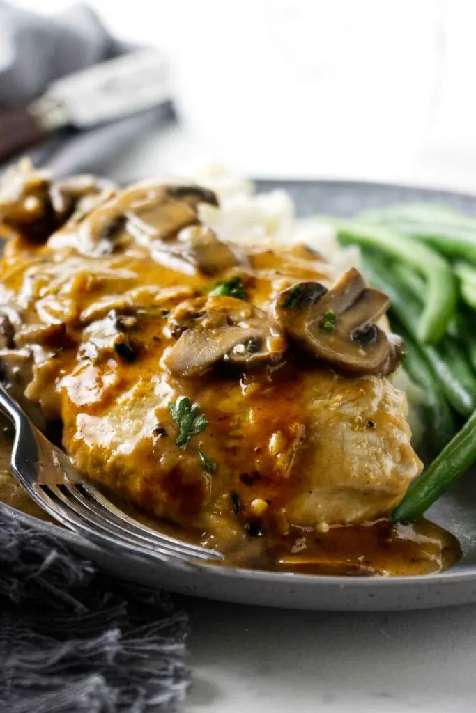 Seared chicken breast with mushroom marsala sauce on a dinner plate.