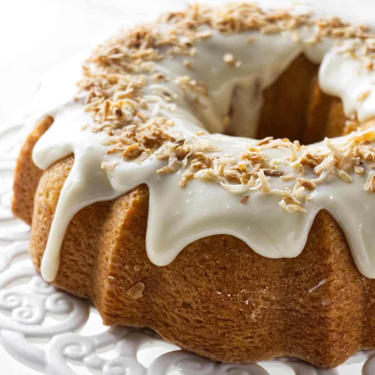 A coconut bundt cake topped with a cream cheese icing and toasted coconut.