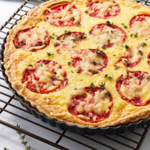 A tomato quiche with caramelized onions on a cooling rack.