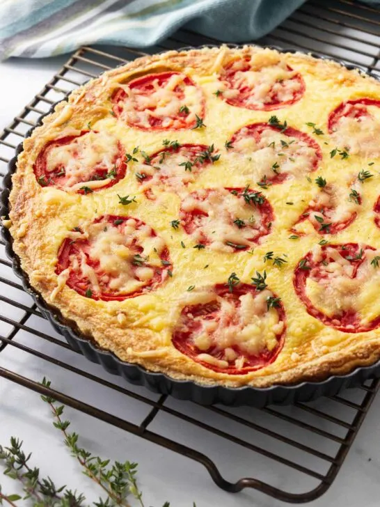 A tomato quiche with caramelized onions on a cooling rack.