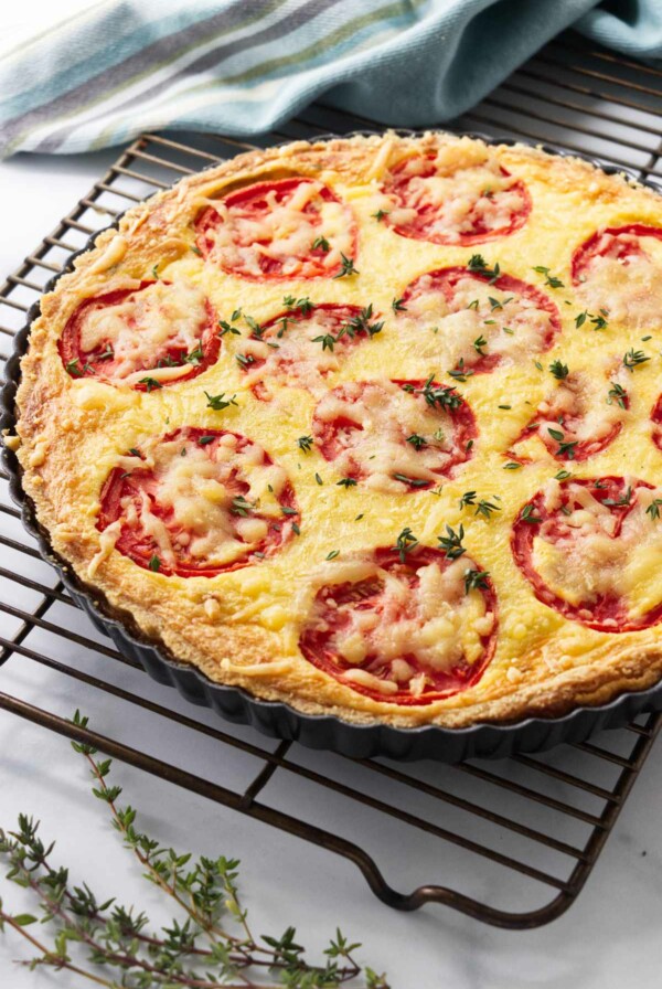 A tomato quiche with caramelized onions on a cooling rack.