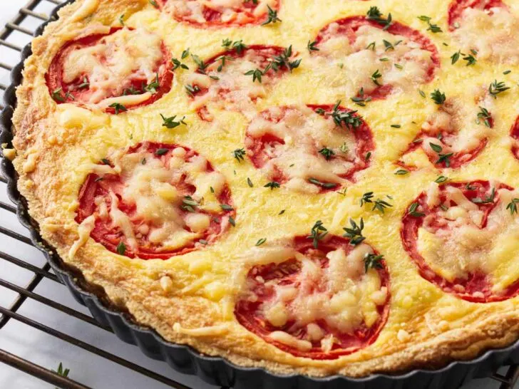 A tomato quiche with caramelized onions on a cooling rack.