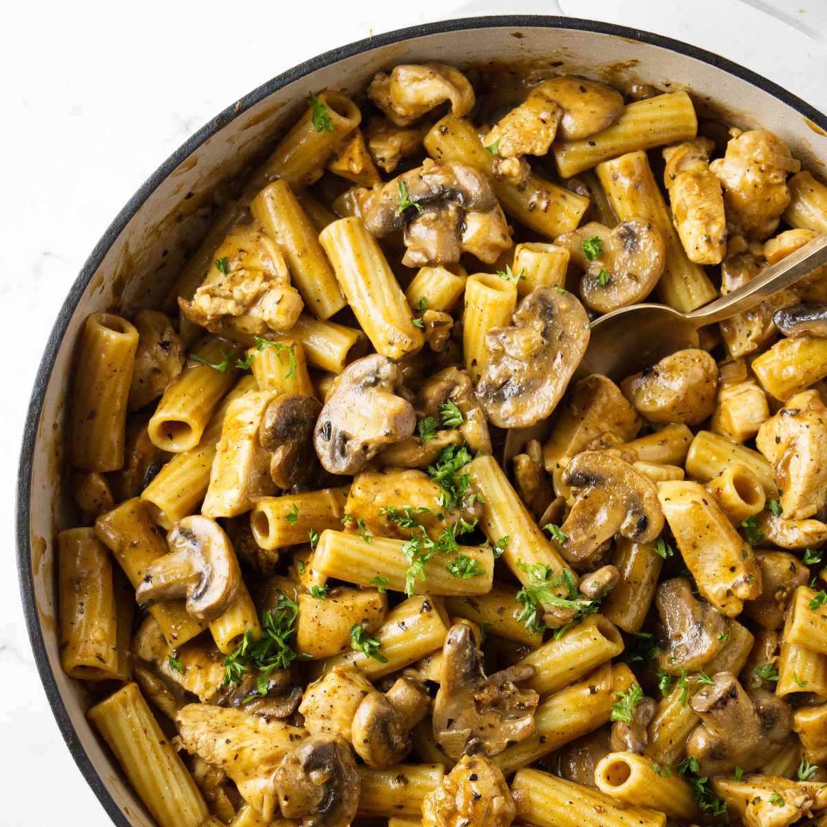 Marsala cream sauce pasta in a skillet with a spoon.