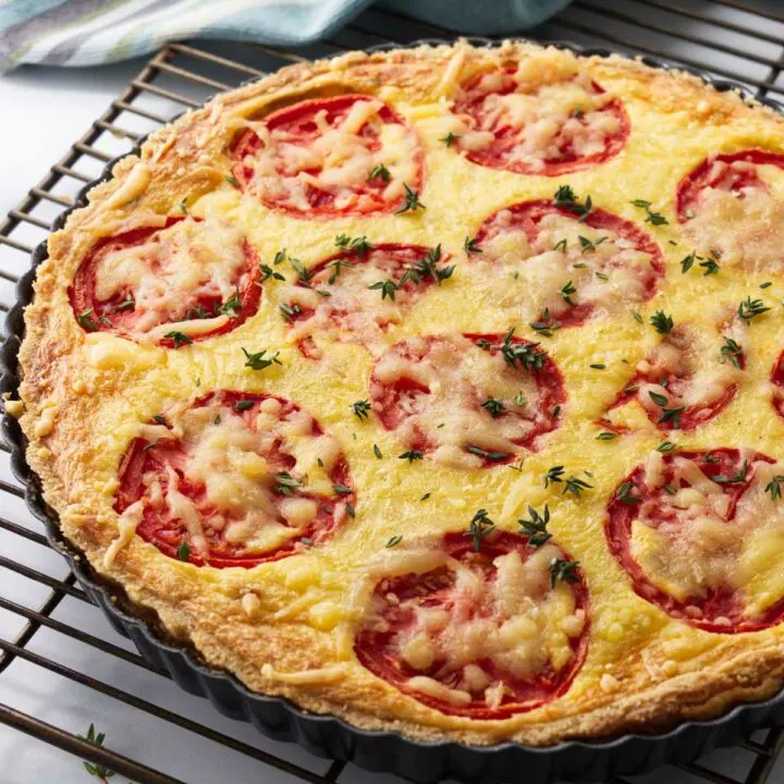A tomato and onion quiche on a cooling rack.