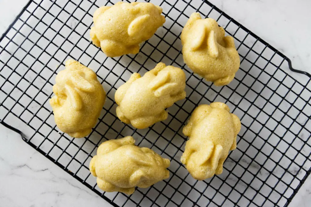 Mini bunny cakelets cooling on a rack.