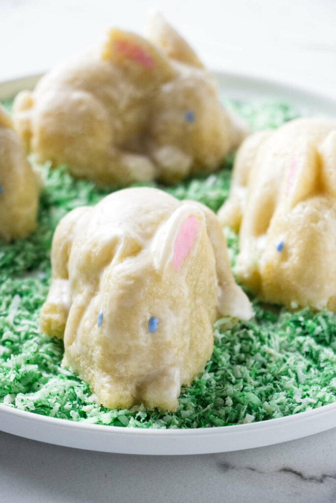 Four mini Easter bunny cakes on a bed of green coconut.