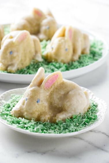 Several small bunny cakes on a bed of green coconut.