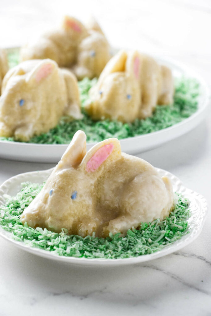 Several small bunny cakes on a bed of green coconut.