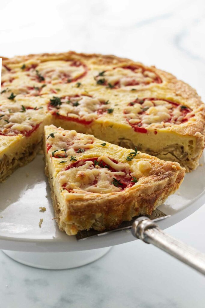 A tomato and onion quiche on a serving platter.