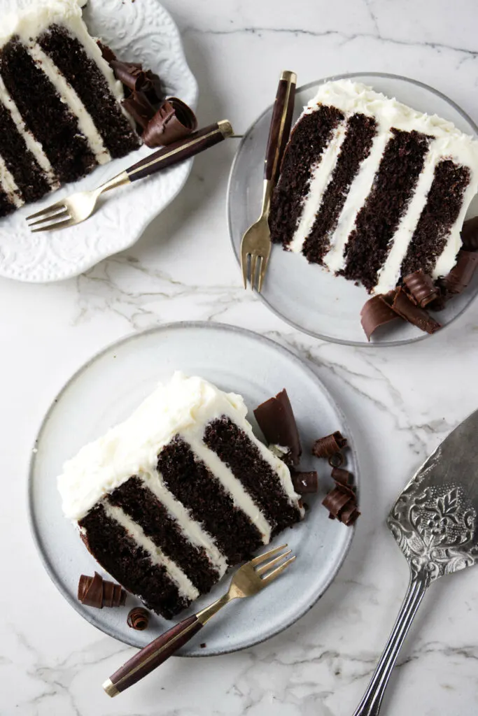Three plates with slices of chocolate cake with cream cheese filling.